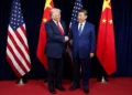 Donald Trump and Xi Jinping shaking hands in front of US and Chinese flags, symbolizing the shift in the 2026 National Defense Strategy
