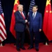 Donald Trump and Xi Jinping shaking hands in front of US and Chinese flags, symbolizing the shift in the 2026 National Defense Strategy