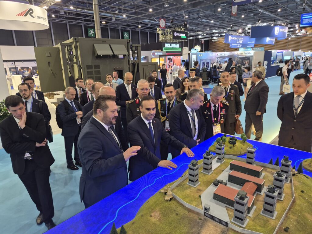 Bakan Mehmet Fatih Kacır Eurosatory 2026 fuarında Koluman standındaki askeri üs maketini inceliyor.