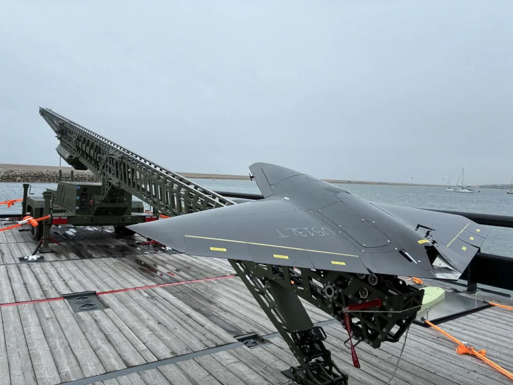 Nyan OWE kamikaze İHA'sı, XV Patrick Blackett gemisinin güvertesine entegre edilen ve saniyede 55 metre fırlatma hızına ulaşabilen özel lançer sisteminin önünde.